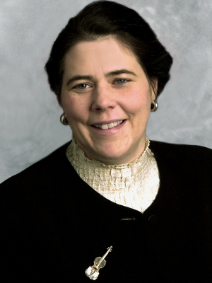 Woman with short black hair wearing a cream blouse and black blazer