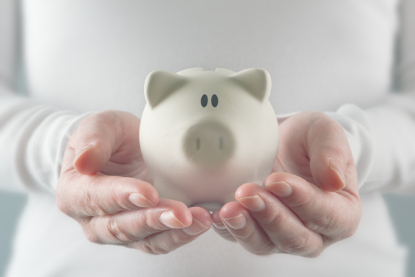 The hands of a woman holding a white piggy bank