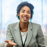 A young Black woman wearing a grey suit jacket speaking