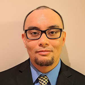 Young man with a goatee and black glasses, wearing a suit