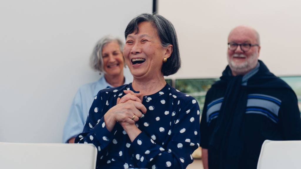 Woman in navy polka dot dress laughing, holding her hands together at her heart