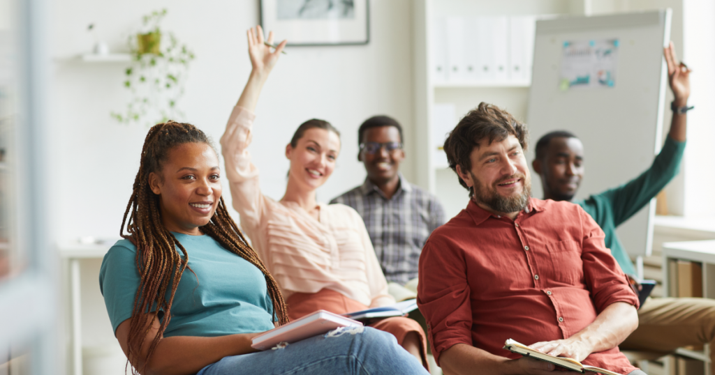 Un groupe de 5 adultes, souriants et assis sur des chaises dans un atelier