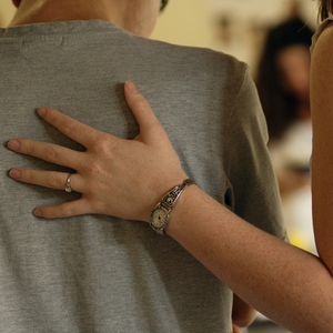 Two people with their backs to the camera and one person has their arm in a caring way over the person's shoulder