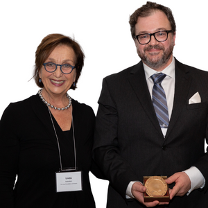 Woman and man standing beside each other, man holding award