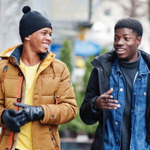 Two young Black men dressed in winter clothes, walking and laughing together