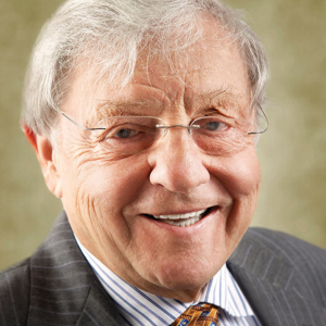 Older man smiling and wearing a suit jacket and tie