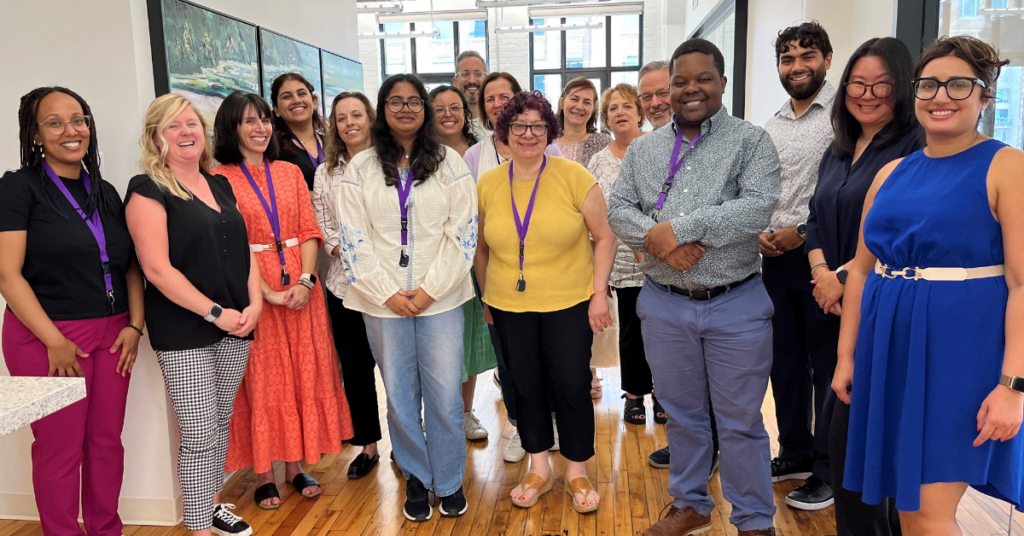 17 co-workers laughing and posing for a photograph