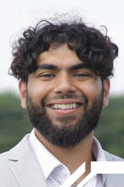 Young man with dark, curly hair and a beard, and who is smiling