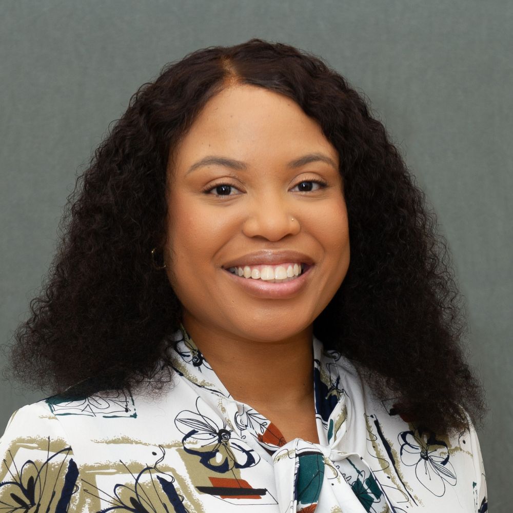 Women with long black curly hair wearing a white, flower-patterned shirt