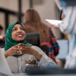 Woman wearing a green hijab talking with a co-worker in an office